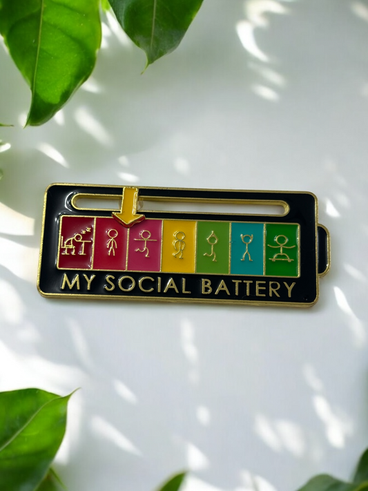 My Social Battery brooch in black with a figurine and yellow arrow